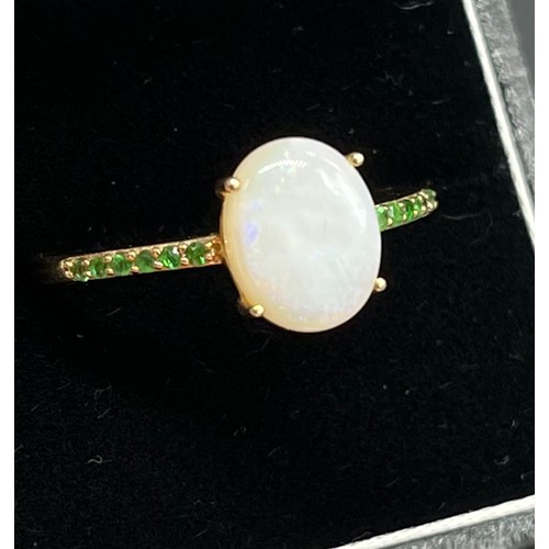 92 - 10ct yellow gold ladies ring set with a large opal stone off set by green tourmaline stone shoulders... 