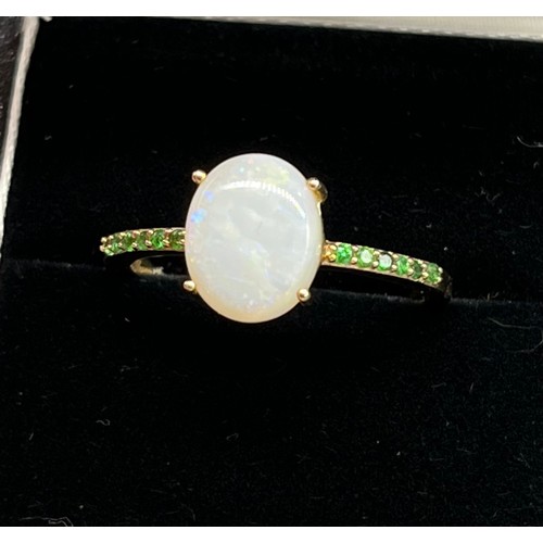 92 - 10ct yellow gold ladies ring set with a large opal stone off set by green tourmaline stone shoulders... 