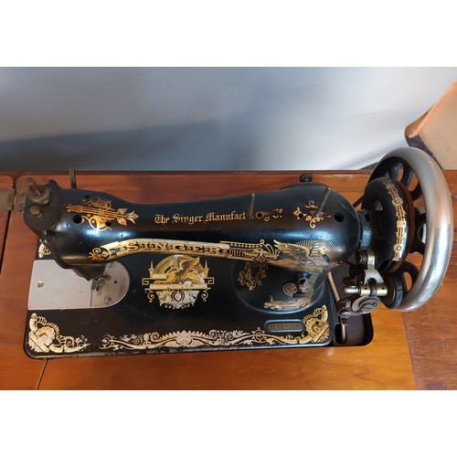 353 - Antique pedal singer sewing machine, raised and supported on a cast iron base. [78x90x44cm]