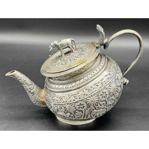 79 - A Colonial Indian Silver tea pot, rested at an angle, highly decorative body, lid detailed with an e... 