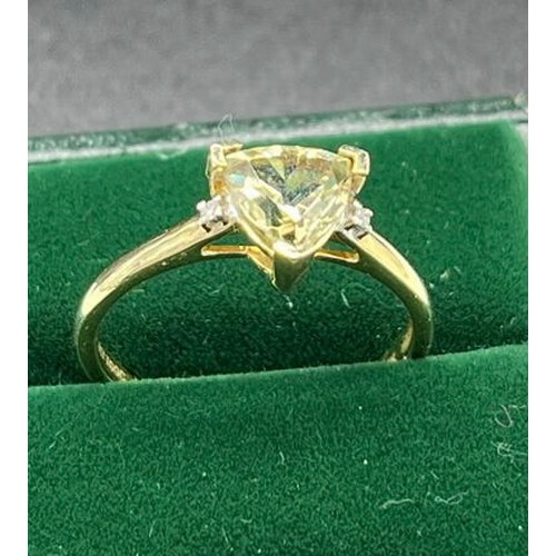 29 - 10ct yellow gold ladies ring set with a triangle cut green topaz off set by two single diamonds to e... 