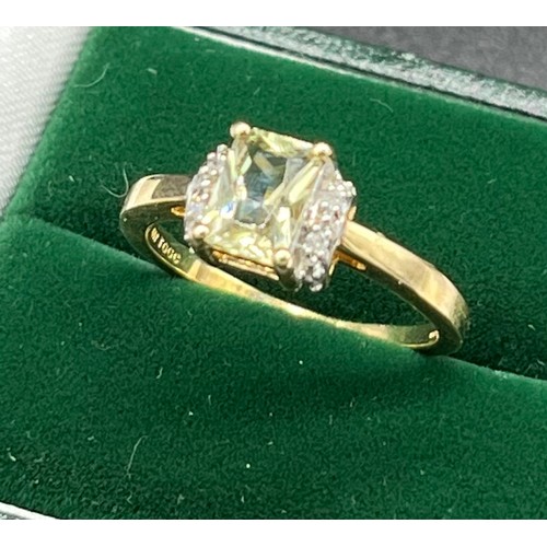 512 - 10ct yellow gold ladies ring set with and Emerald cut pale green topaz stone off set by diamond shou... 