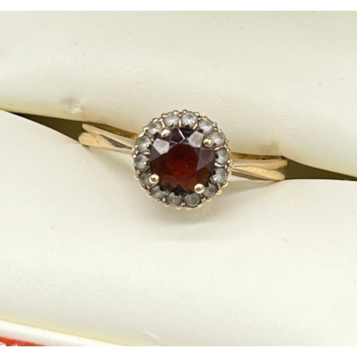 8 - 9ct yellow gold ladies ring set with a round cut garnet off set by white quartz stones. [Ring size R... 