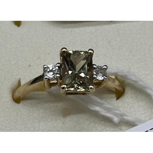 40 - 10ct yellow gold ladies ring set with a emerald cut pale green topaz stone off set by white spinel s... 