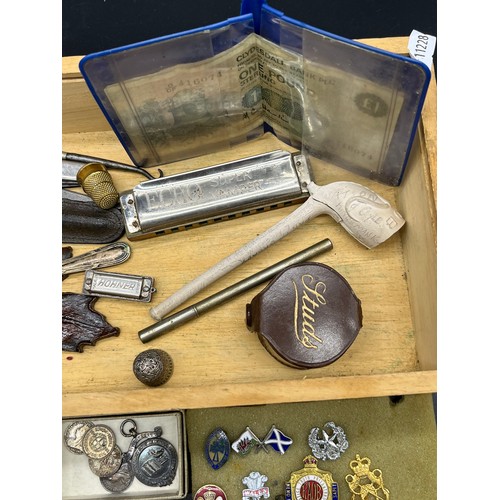 44 - Box of interesting odds to include miniature harmonica, Military cap badges, Three silver fob medals... 