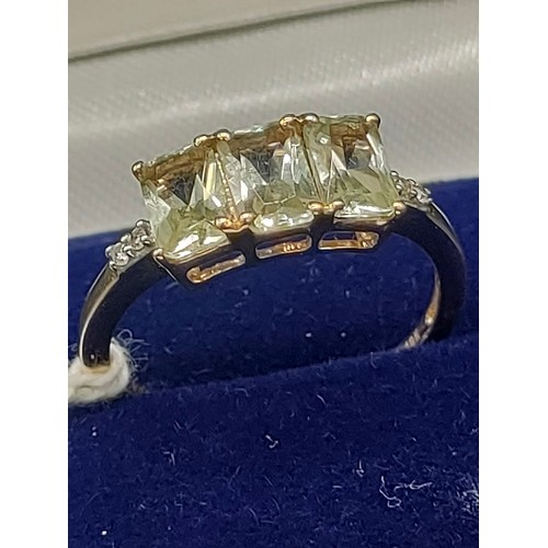 30 - A 10ct yellow gold ladies ring set with three green topaz stones off set by diamond shoulders. [Ring... 