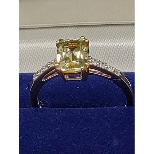 46 - 10ct yellow gold ladies ring set with a large green topaz stone off set by White spinel stone should... 