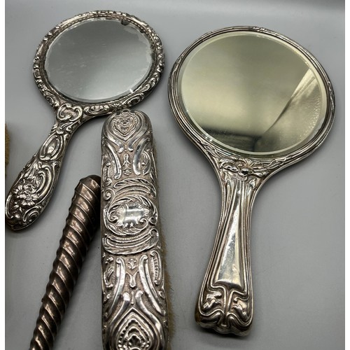 39 - A Mixed lot of silver dressing table items to include two highly decorative hand mirrors and two han... 