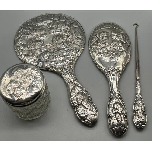 29 - Four Silver ornate cherub design dressing table items. Two hand mirrors, button hook and lidded pres... 