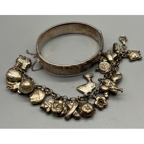 73 - Antique silver bangle together with a silver charm bracelet full of silver charms.