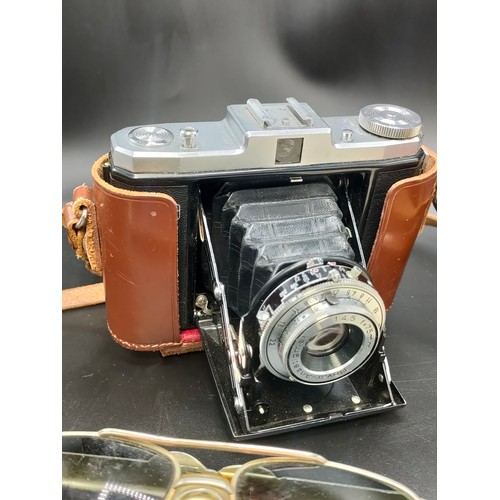 64 - A tray containing vintage sunglasses and zeiss ikon nettar camera.