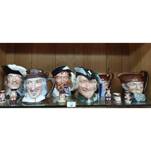 87 - Shelf of Royal Doulton toby jugs and Beswick pig band figure