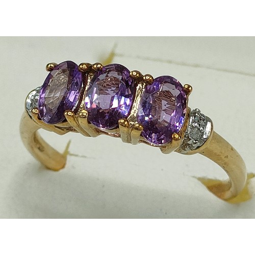 42 - 9ct yellow gold ring set with three purple topaz stones off set by diamond shoulders. [Ring size Q] ... 