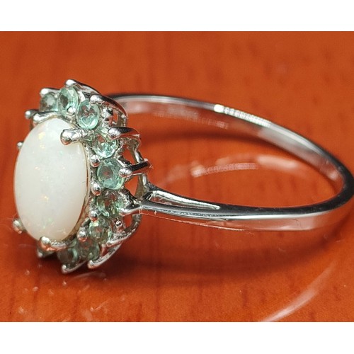 8 - 10ct white gold ladies ring set with a single Australian white opal surrounded by pale green stones.... 