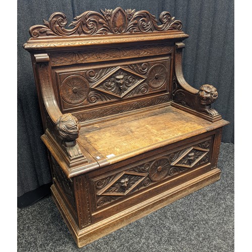 912 - Victorian oak monks bench, carved foliate design to the top above a carved mask to the centre and li... 