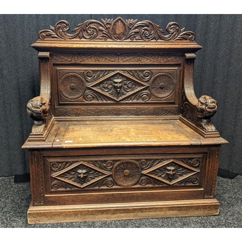 912 - Victorian oak monks bench, carved foliate design to the top above a carved mask to the centre and li... 