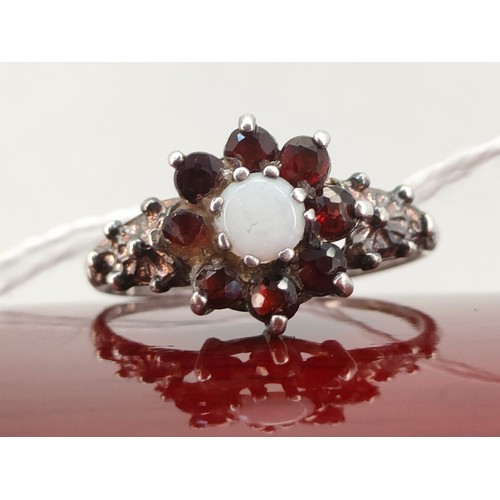 40A - Sheffield silver ladies ring set with a single opal surrounded by garnet stones. [Ring size P]