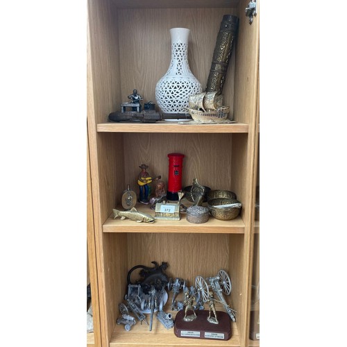 372 - Three shelves of collectables; Cast metal revolver kid's gun, Blanc de Chine vase, Cast iron hand pa... 