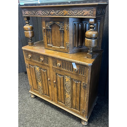 780 - 20th century Oak court cabinet. Vine and grape trims to top section and doors. [147x105x47cm]