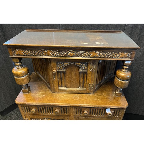 780 - 20th century Oak court cabinet. Vine and grape trims to top section and doors. [147x105x47cm]