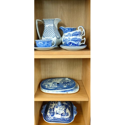 791 - Three shelves of blue and white wares; lidded tureen, Willow pattern drip dish and Spode cups and sa... 