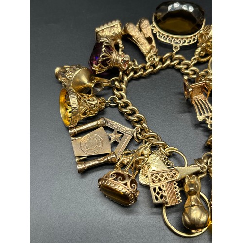 1103 - A Heavy antique 9ct yellow gold charm bracelet fitted with a collection of 9ct yellow gold charms, a... 