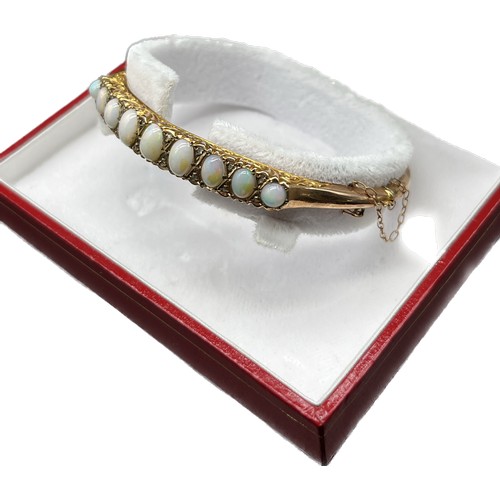 4 - 9ct yellow gold bangle fitted with 9 varying sized opals and small diamond chips [6.62x4.68mm- large... 