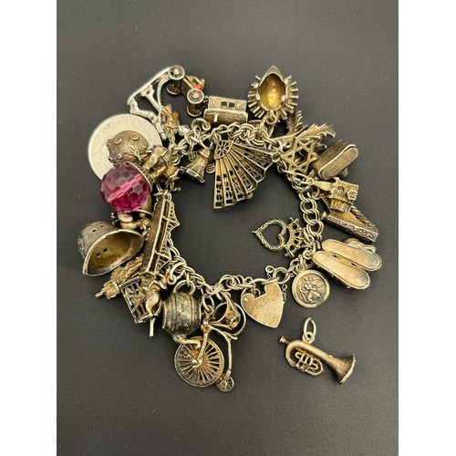 70 - Antique and heavy silver charm bracelet and charms, approximately 30 charms. [96.38grams]