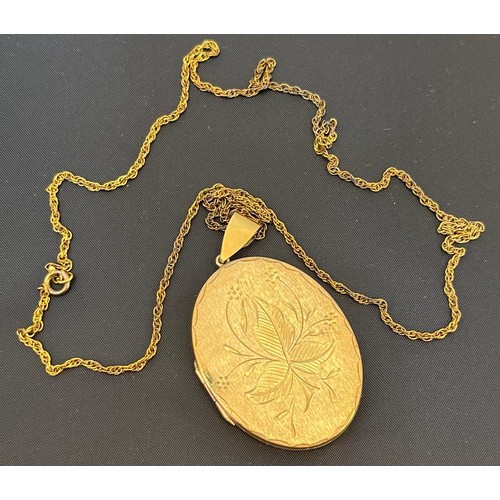 559 - A 9ct gold locket, engraved decoration and on a long chain marked 9c. [18.36grams]