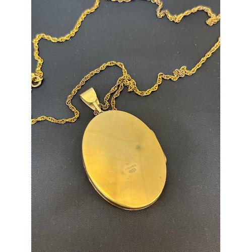 559 - A 9ct gold locket, engraved decoration and on a long chain marked 9c. [18.36grams]