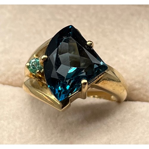 108 - 9ct yellow gold ring set with a large dark blue topaz stone and small green/ blue round cut gem ston... 