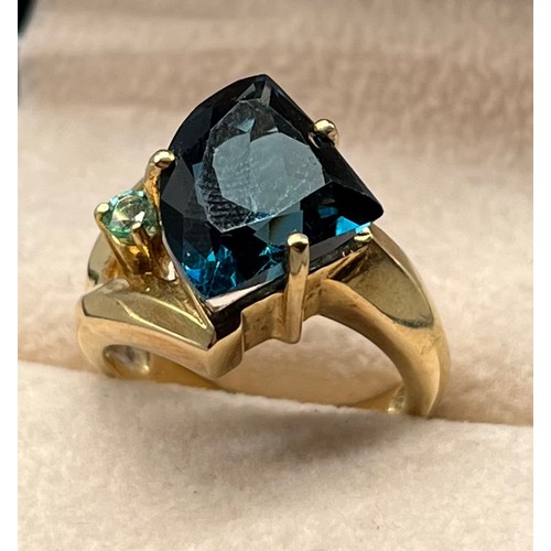 108 - 9ct yellow gold ring set with a large dark blue topaz stone and small green/ blue round cut gem ston... 