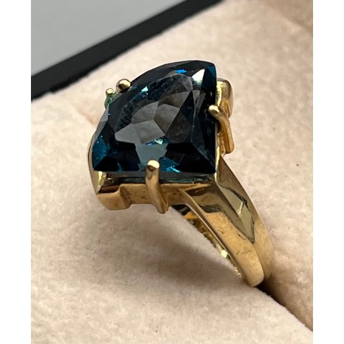 108 - 9ct yellow gold ring set with a large dark blue topaz stone and small green/ blue round cut gem ston... 