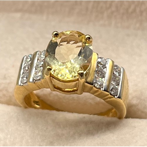 103 - 18ct yellow gold ring set with an oval cut gem and two rows of round cut diamonds to each shoulder. ... 