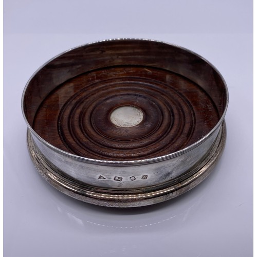 9 - A modern silver wine coaster
JAC, London 1986 of plain form threaded rim
mahogany base with silver b... 