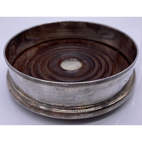 9 - A modern silver wine coaster
JAC, London 1986 of plain form threaded rim
mahogany base with silver b... 