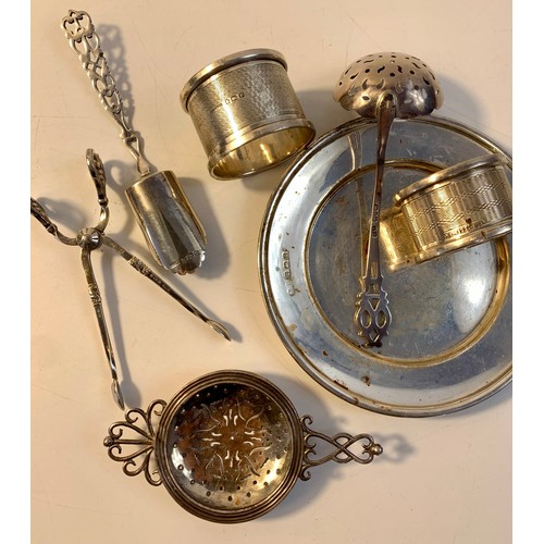 59 - Mixed lot of silver to include silver dish, napkin rings, tea strainer, small ladle, sugar tongs and... 