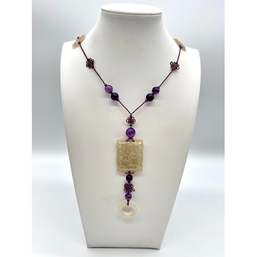 4 - A Chinese jade and amethyst bead long necklace, principal pierced rectangular panel , silk cord with... 