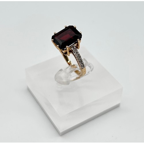 25 - 9ct yellow gold ring with emerald-cut garnet flanked by diamonds, size L [4.40g]