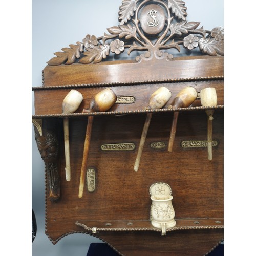 87 - Large black forest heavily carved pipe rack with inlays include s smoking pipes & 1900s bone cup.