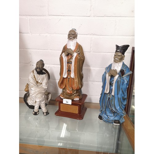 94 - 3 Oriental figures one on ceramic oriental plinth .