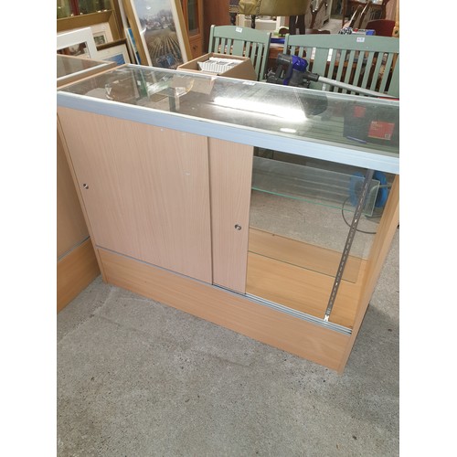 237 - A Large Glass Shop Cabinet (122x97x45cm) With Glass Front Glass Shelves And Sliding Access Doors