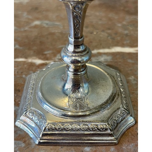 36 - A Pair of George I silver tapersticks. Each on a square base with in-curved angles, with baluster st... 