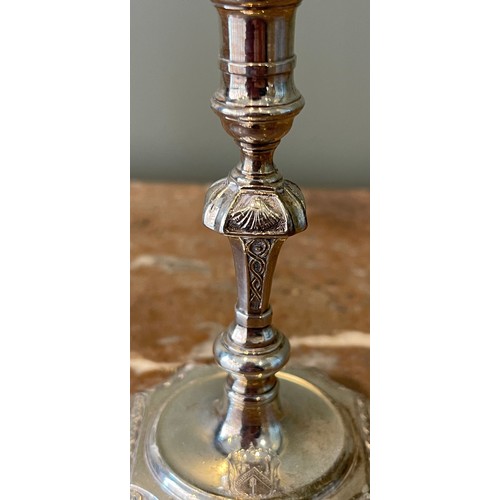 36 - A Pair of George I silver tapersticks. Each on a square base with in-curved angles, with baluster st... 