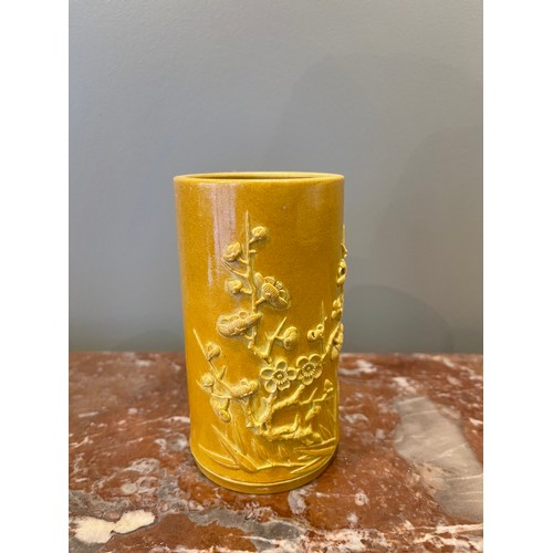 70 - A yellow cylindrical Chinese brush pot of bamboo form with bamboo and prunus blossom relief decorati... 