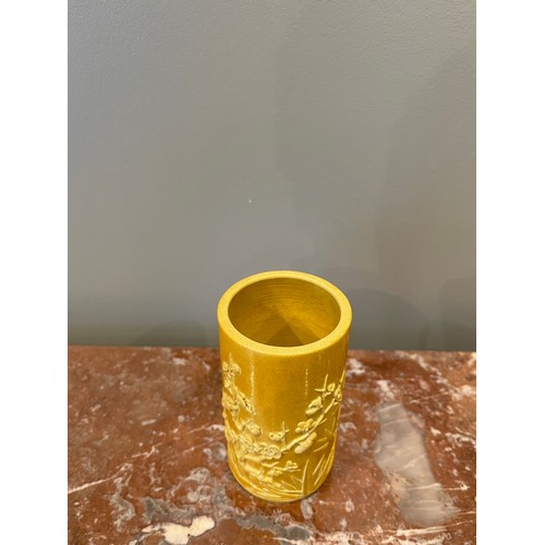 70 - A yellow cylindrical Chinese brush pot of bamboo form with bamboo and prunus blossom relief decorati... 