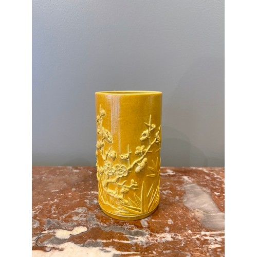 70 - A yellow cylindrical Chinese brush pot of bamboo form with bamboo and prunus blossom relief decorati... 