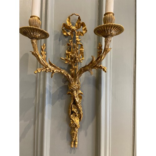 An extremely fine pair of French gilt-bronze twin-branch wall lights of Louis XVI. Late 18th century. Drilled and wired for electricity. Each terminating in two hanging tassels surmounted by grape-clusters and vine leaves, rising into part-fluted stems cast as vines knotted below twin scrolling branches of budding vines, finishing in piled grape clusters and buds, and topped by a trefoil ribbon. Stamped to the reverse: '888'.