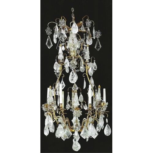 A French ormolu and rock crystal six-light chandelier (mid-20th century). Of Louis XV style, the open cage centred by an upswept faceted sprig with ormolu finial, the shaped branches with flowerhead shaped drip pans and plain nozzles interspersed with further branches hung with droplets, faceted pendants and conforming sprigs, and terminating with a pear-shaped boss, the crown with central faceted baluster with variously shaped droplets, electrified.