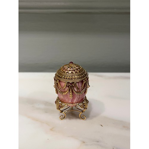 90 - A small jewelled hardstone egg on a stand in Russian taste. Banded pink hardstone. Gold setting with... 